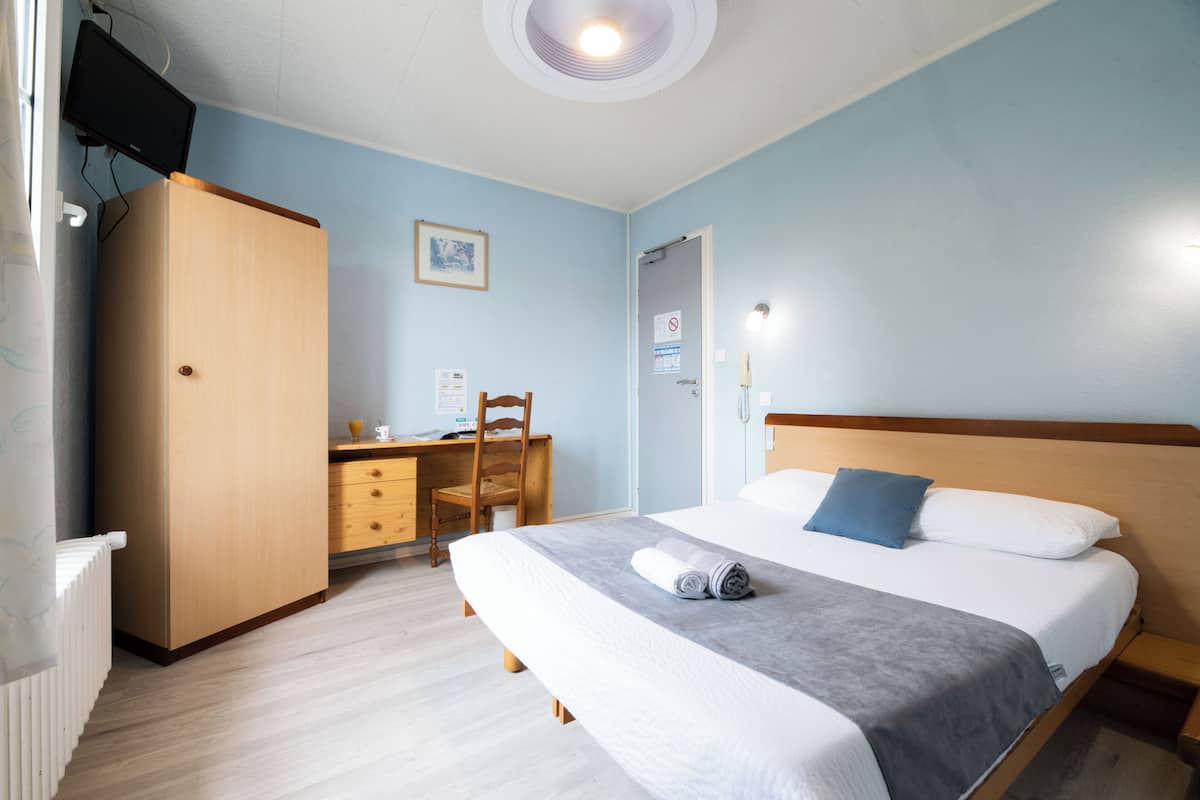 Une chambre à coucher comprenant un lit, un bureau, une chaise et une armoire.