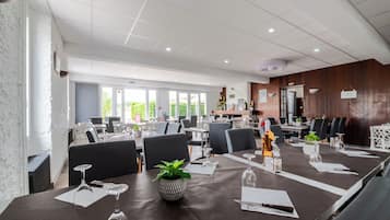 Ein moderner Essbereich mit gedeckten Tischen, kombiniert mit natürlichem und künstlichem Licht, und Blick ins Freie durch große Fenster.