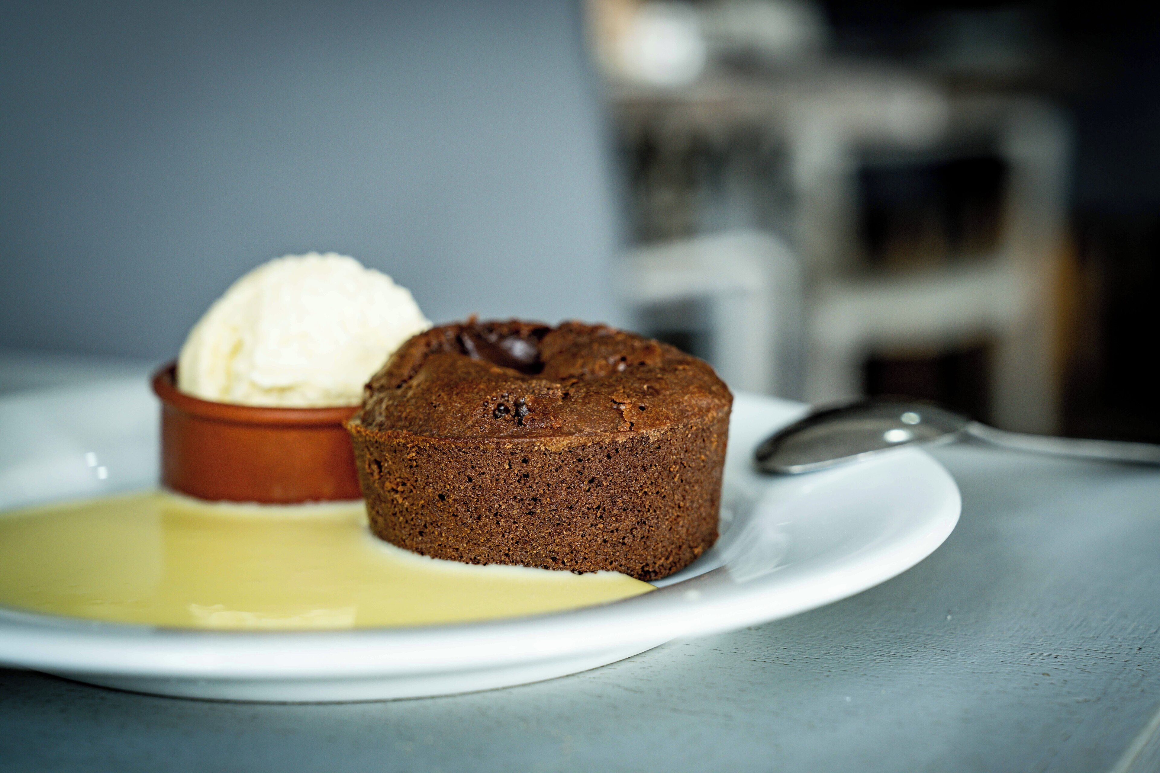 Un plato de postre con pastel de chocolate y una bola de helado de vainilla.