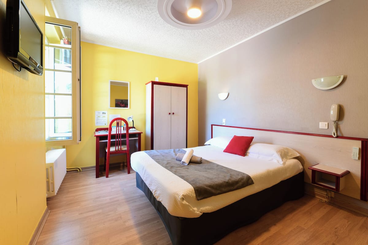 Une chambre d’hôtel comprenant un lit, un bureau, une chaise, une armoire et un téléviseur.