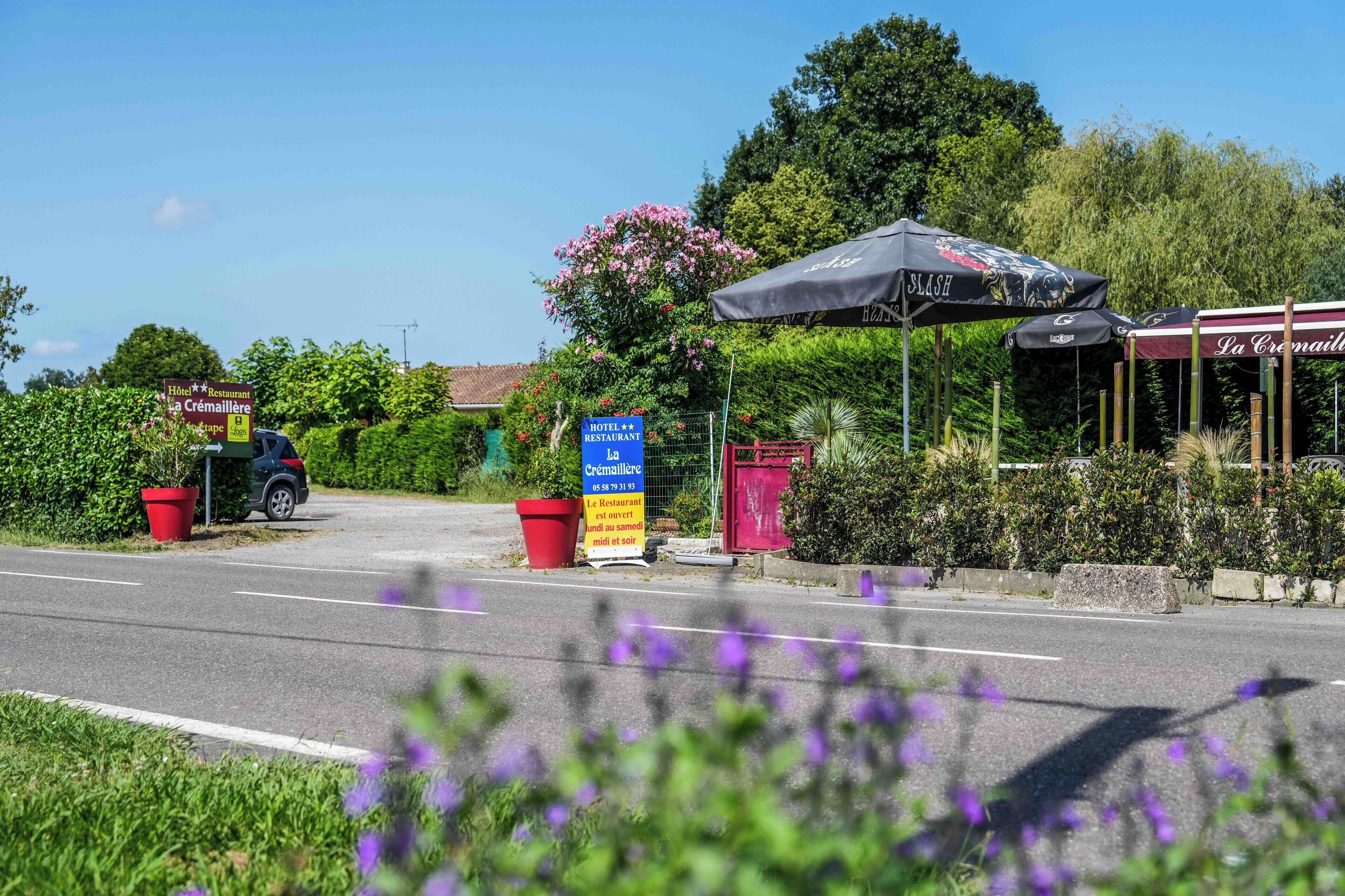 Vista desde la carretera de un hotel llamado "La Crémaillère", con un cartel que indica que es hotel y restaurante.