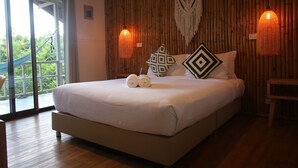 A large bed with white linens, two decorative pillows, and a pair of rolled towels. There are two wall-mounted lamps with a woven design. - Bluerama Resort (Ko Pha-ngan)