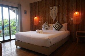 A large bed with white linens, two decorative pillows, and a pair of rolled towels. There are two wall-mounted lamps with a woven design. - Bluerama Resort (Ko Pha-ngan)