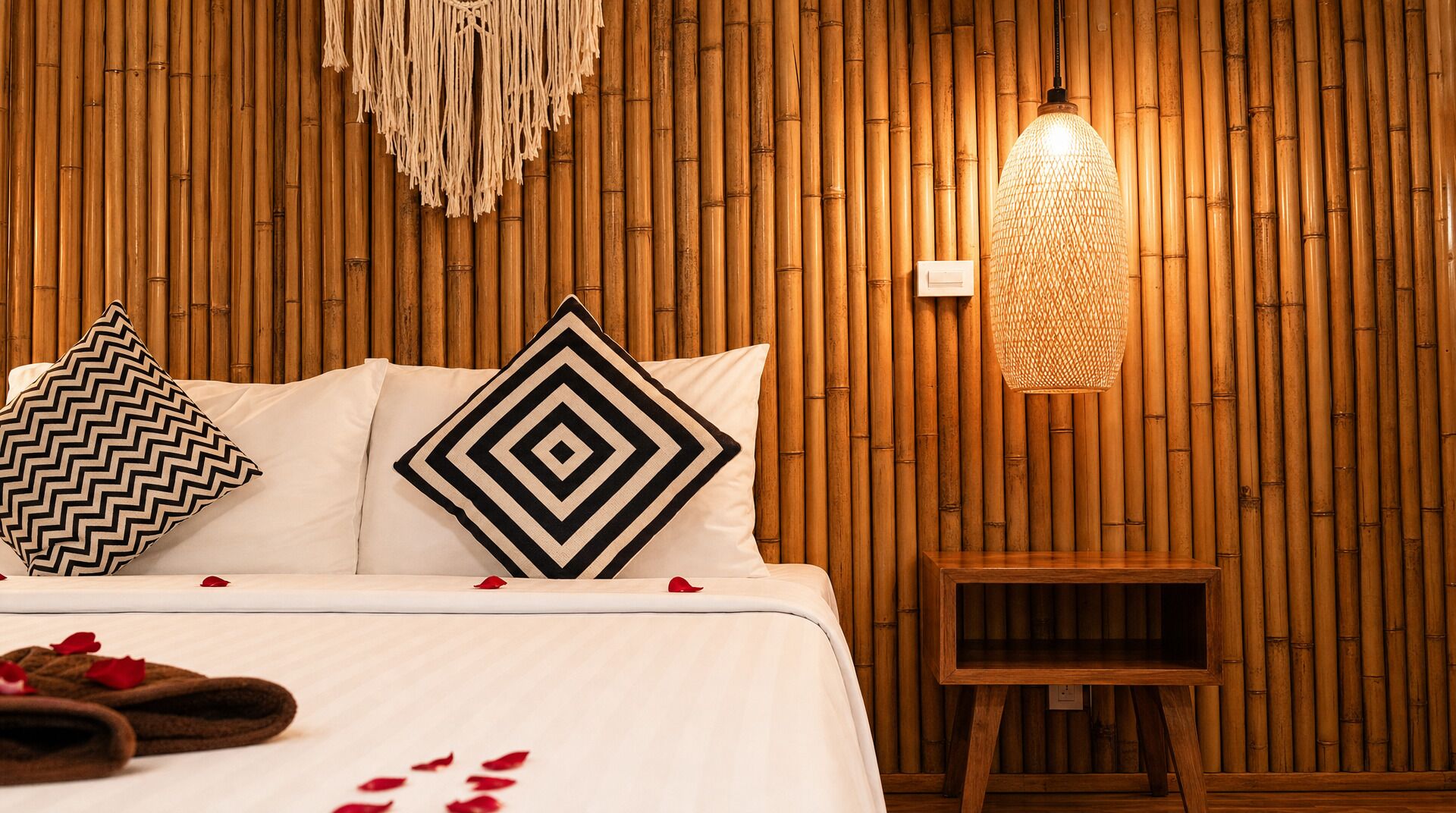 Una cama con dos almohadas, una mesita de noche y una pared con diseño de bambú.