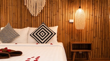 Una cama con dos almohadas, una mesita de noche y una pared con diseño de bambú.