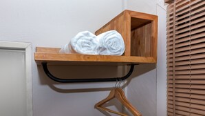 A wooden shelf with rolled white towels and a wooden hanger. - Bluerama Resort (Ko Pha-ngan)