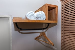 A wooden shelf with rolled white towels and a wooden hanger. - Bluerama Resort (Ko Pha-ngan)