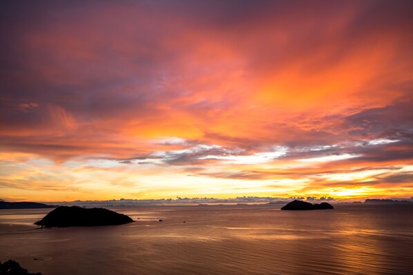A sunset over a calm body of water with two islands in the distance. - Bluerama Resort (Ko Pha-ngan)