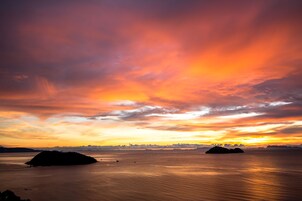 Un atardecer sobre aguas tranquilas, con dos islas a lo lejos.