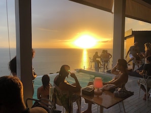 A sunset view from a poolside area with people seated at tables, overlooking the ocean. - Bluerama Resort (Ko Pha-ngan)
