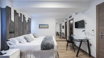 A modern hotel room with a bed, bedside table, desk, and a TV.