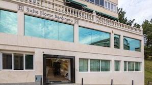 Een hotel genaamd 'Suite Home Sardinero' met een moderne gevel, grote ramen en een balkon met hekwerk.