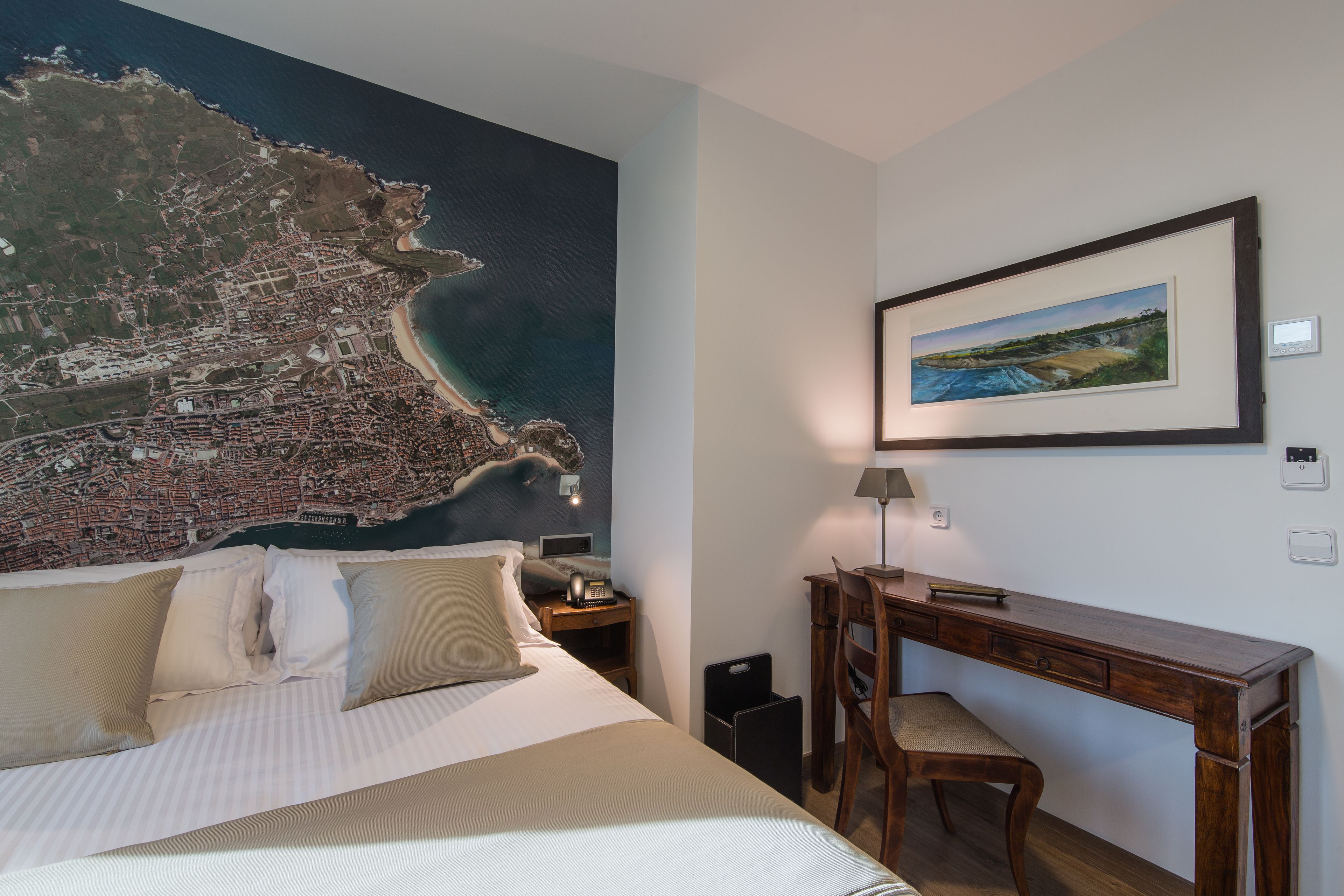 Habitación de hotel con una cama grande, un escritorio, una silla, un mapa en la pared y un cuadro enmarcado.