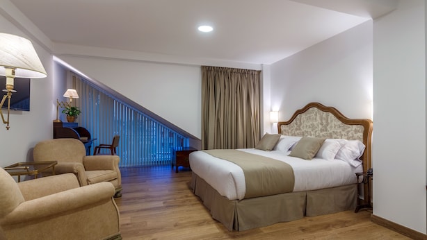 Een hotelkamer met een bed, een stoel, een bureau en een trap.