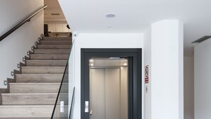 Een modern interieur met een houten trap, een vloerkleed met zebraprint en een gesloten lift.