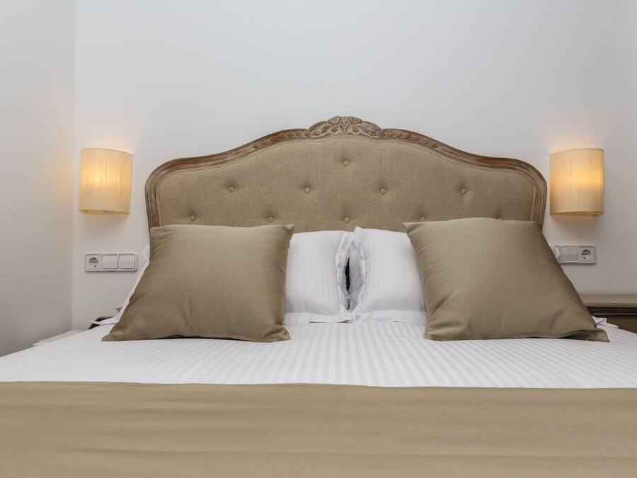 A neatly made bed with a tufted headboard, two beige pillows, and a white duvet.