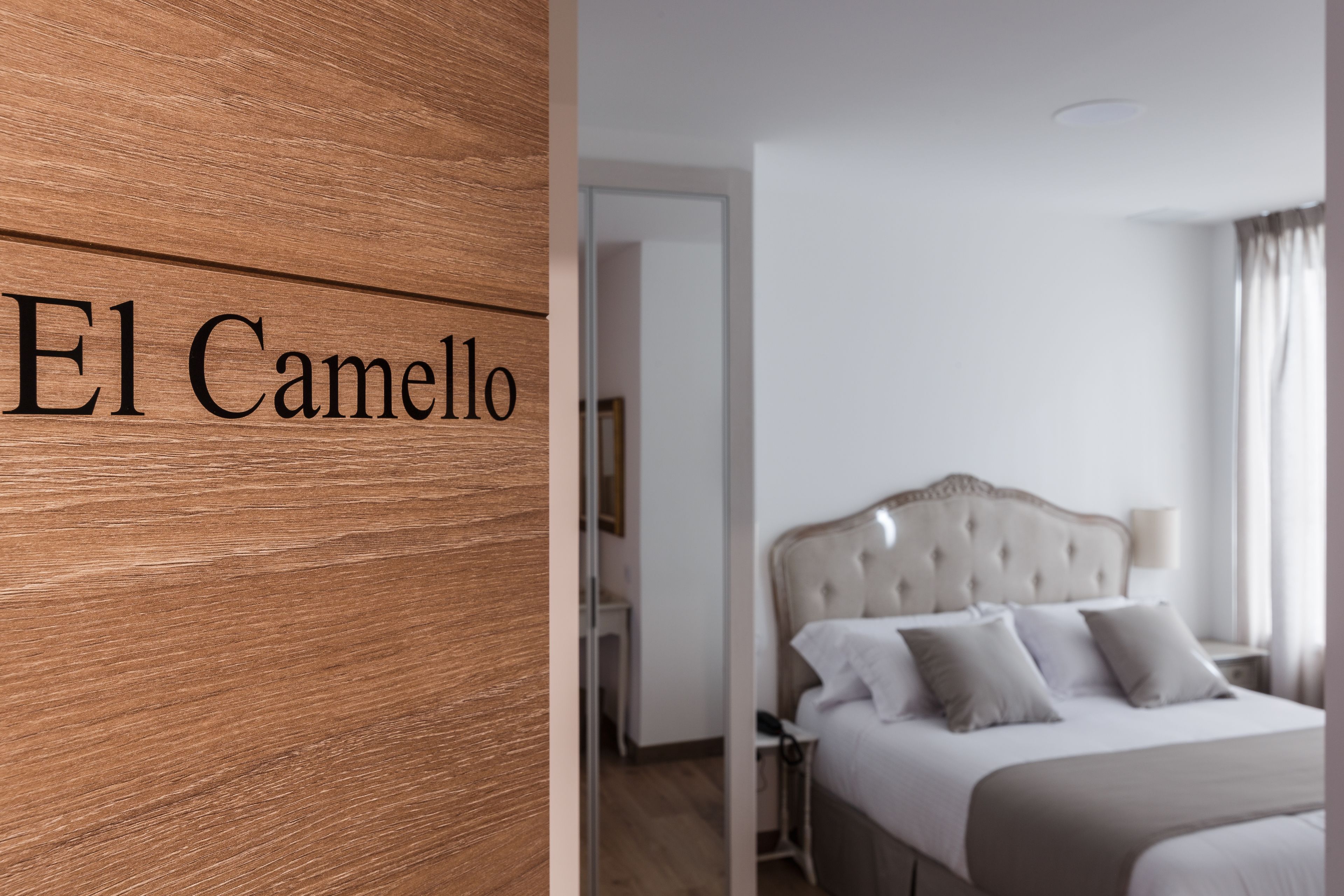 Habitación de hotel con pared de madera y cama con cabecera capitonada.