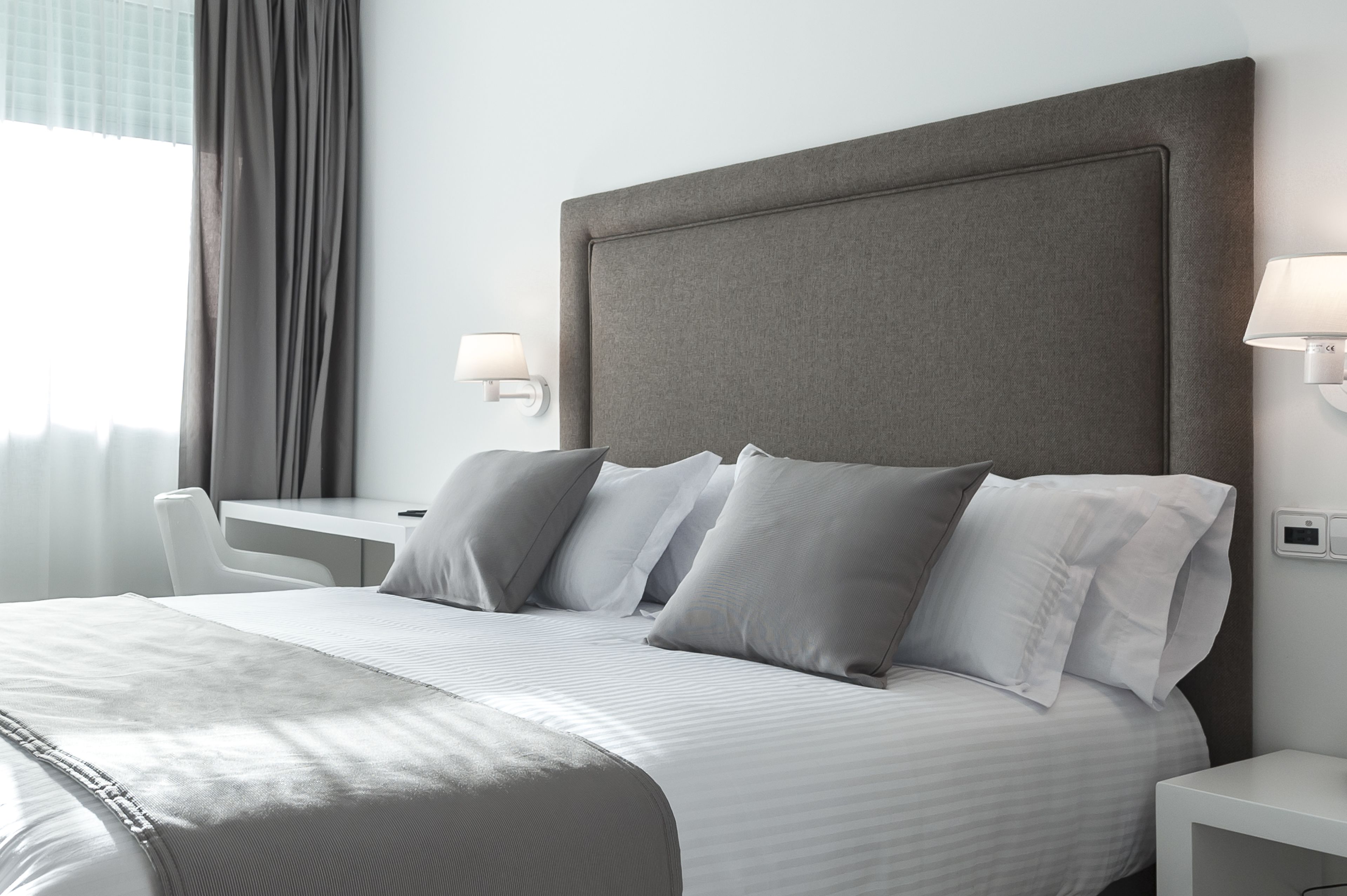 Una habitación de hotel moderna con una cama grande, dos mesitas de noche, un escritorio y una silla.