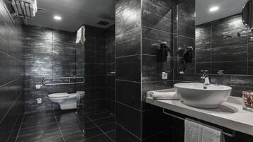 Een moderne badkamer met een ruime wastafel, toilet en douche.