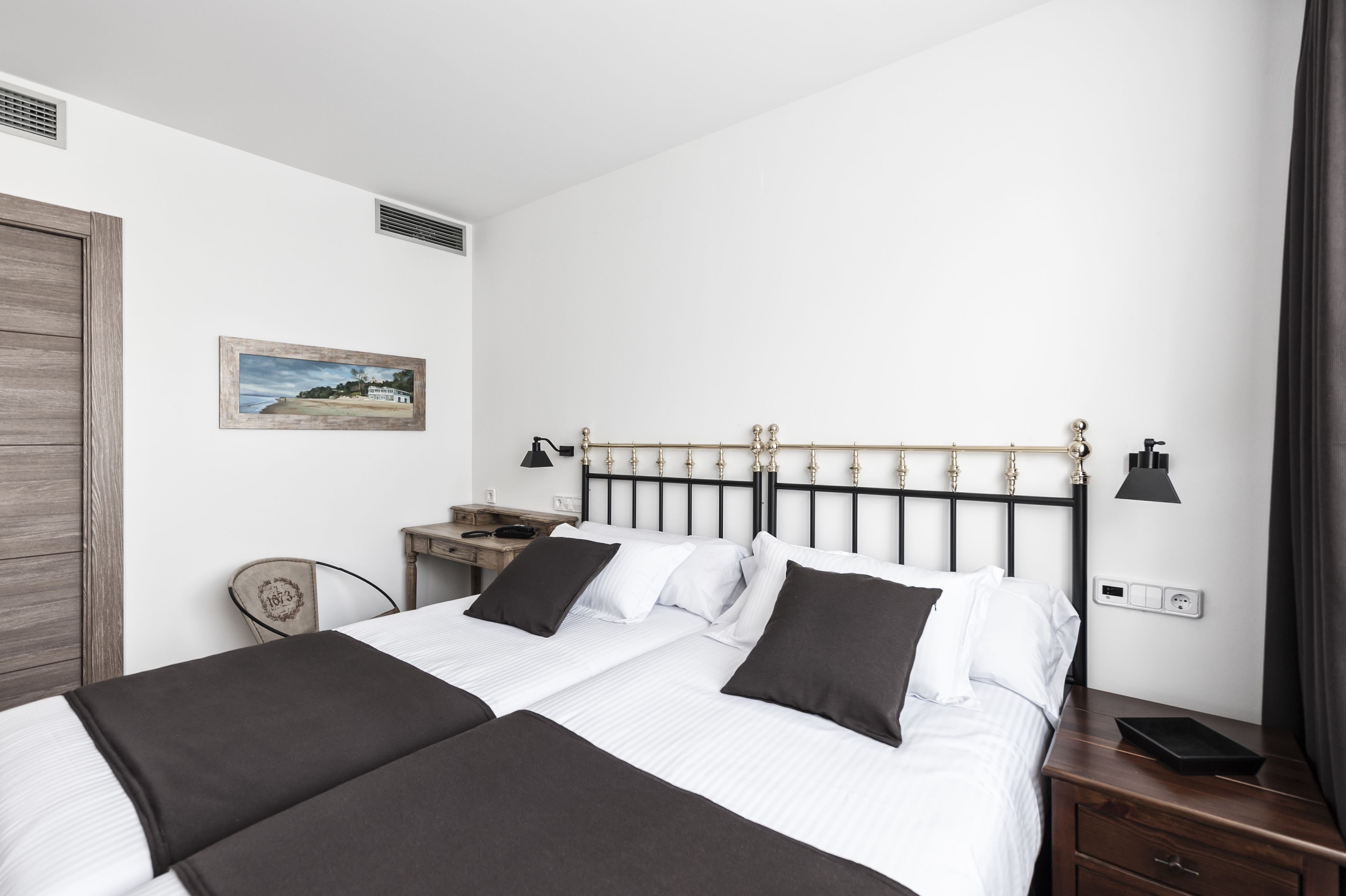 A hotel room with two beds, a desk, a chair, and a nightstand.