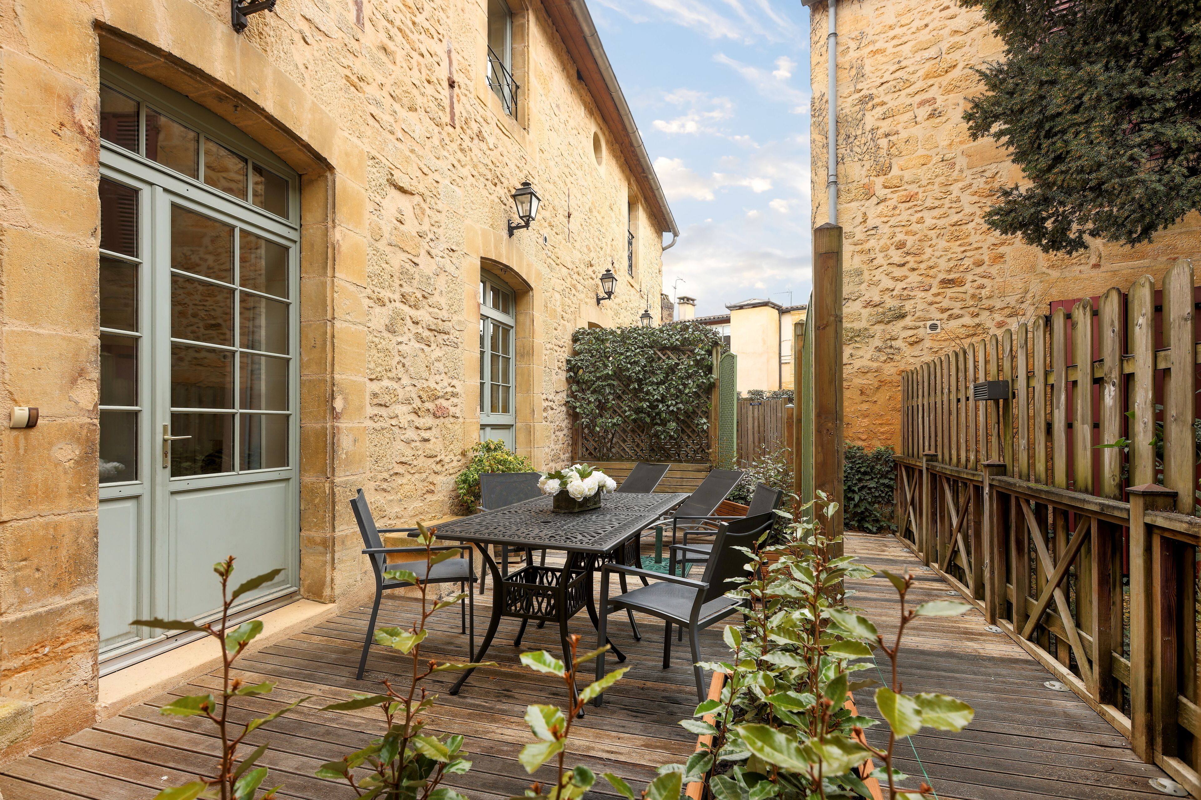 A stone building with a wooden deck, outdoor seating, and a wooden fence.