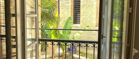 An open balcony with a view of a brick building and a garden.