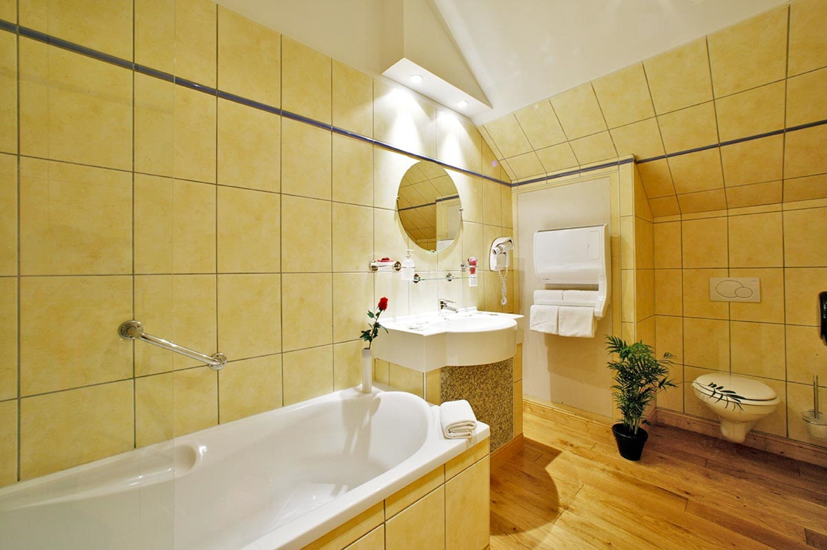 A bathroom with a bathtub, sink, mirror, and toilet.