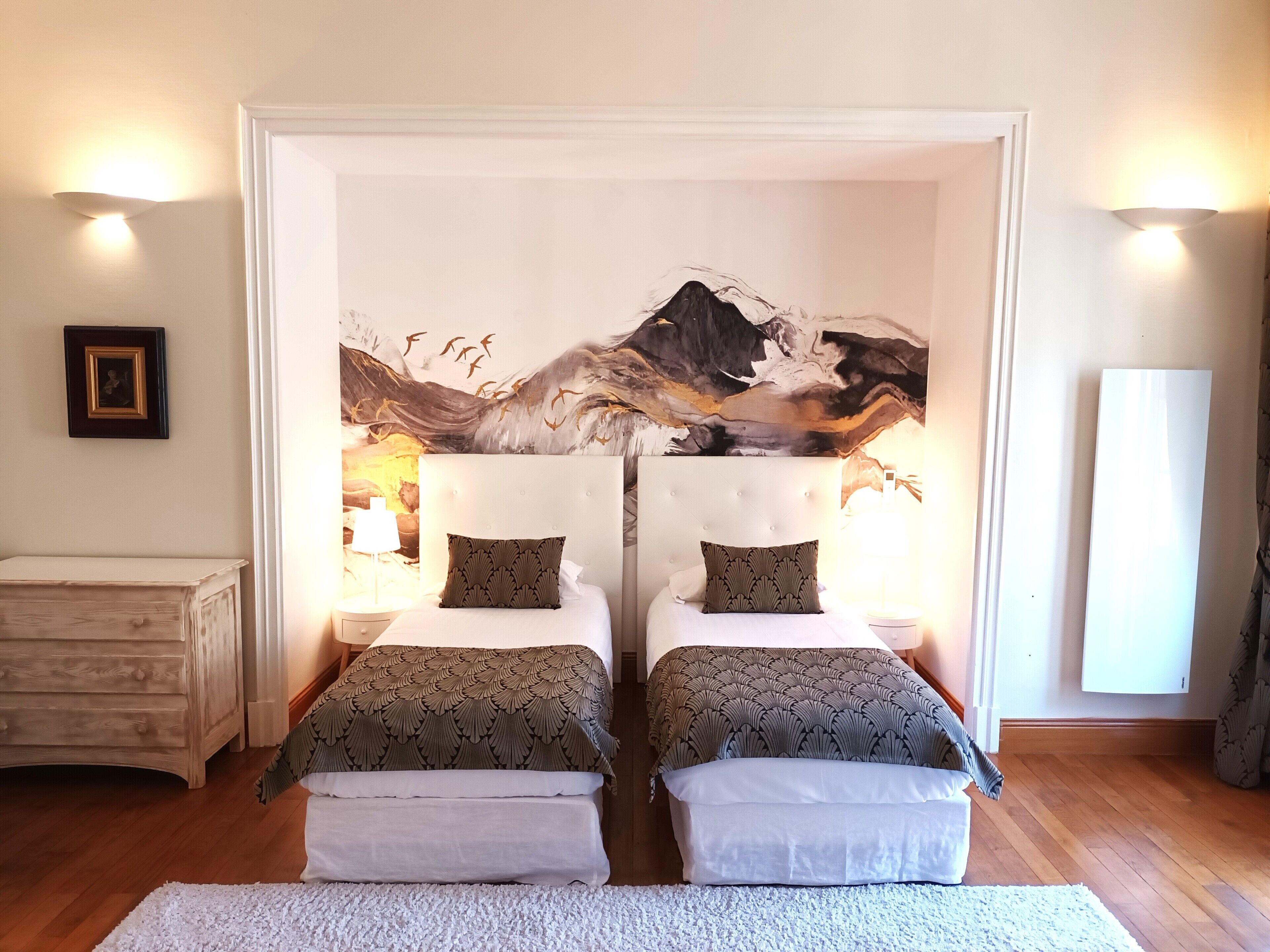 Habitación doble con dos camas, un mural abstracto grande en la pared y suelo de madera.