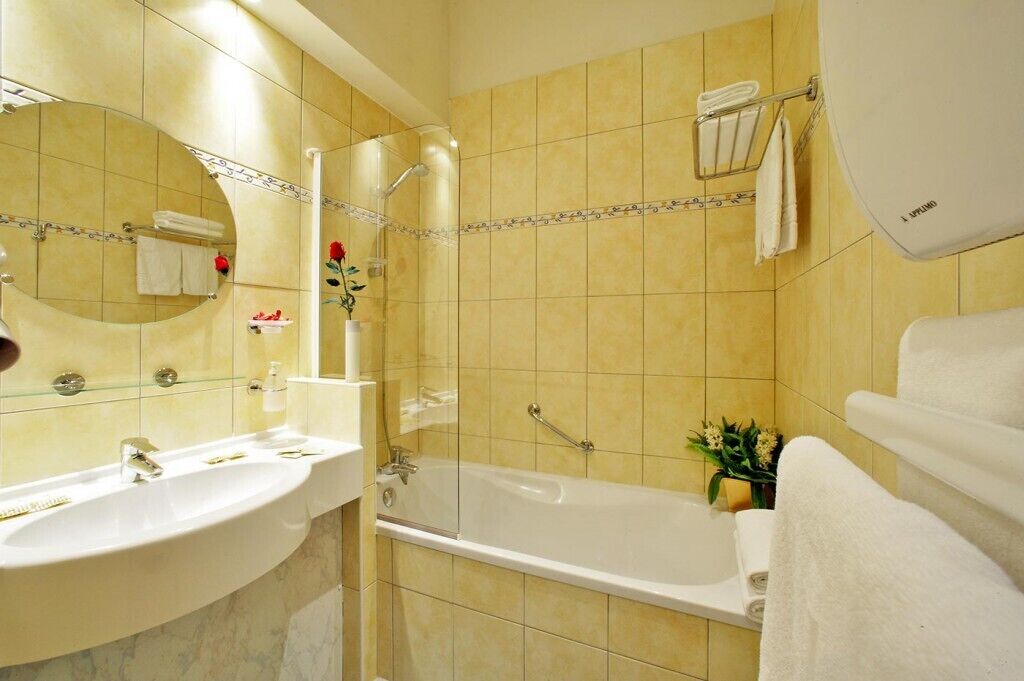 A bathroom with a sink, mirror, shower, and bathtub.