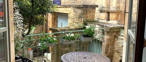 Un patio con un edificio de piedra, una mesa redonda y dos sillas.