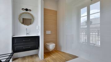 Ein modernes Badezimmer mit einem schwarzen Waschtisch, einer Wand aus Holzpaneelen, einer weißen Toilette und einem großen Fenster mit Blick nach außen.