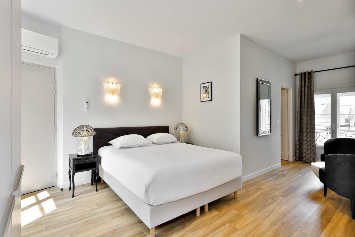Une chambre à coucher moderne avec un grand lit, des lampes de chevet, une table de chevet et une vue sur l’extérieur.