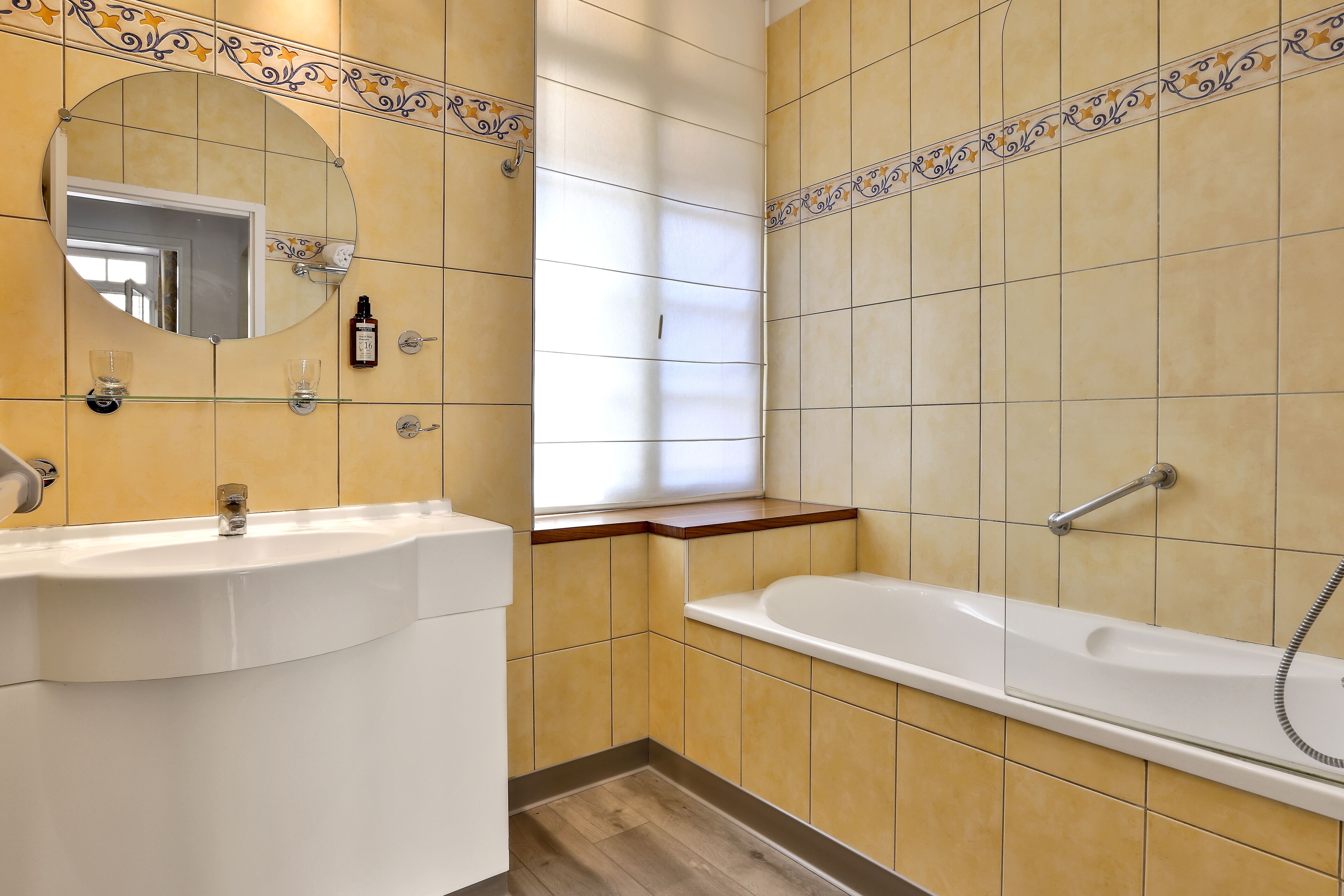 Un baño con lavamanos, espejo y bañera.