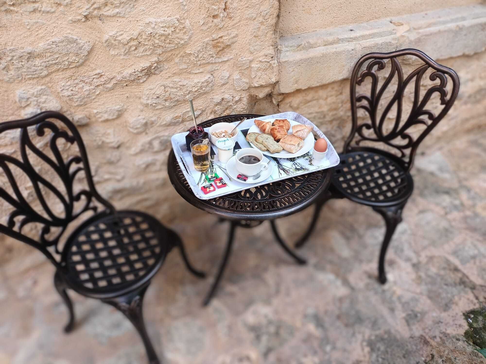 A small round table with a tray of food and two black metal chairs.