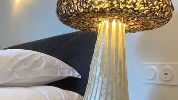 A lamp with a textured, patterned shade on a bedside table in a hotel room.