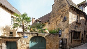 Um edifício histórico de pedra com uma porta verde, uma placa com a inscrição "Rue L. Roux" e uma rua de paralelepípedos.
