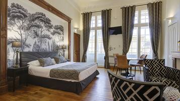 Un dormitorio con una cama grande, un escritorio y una silla. Hay un mural en la pared y una ventana con cortinas.