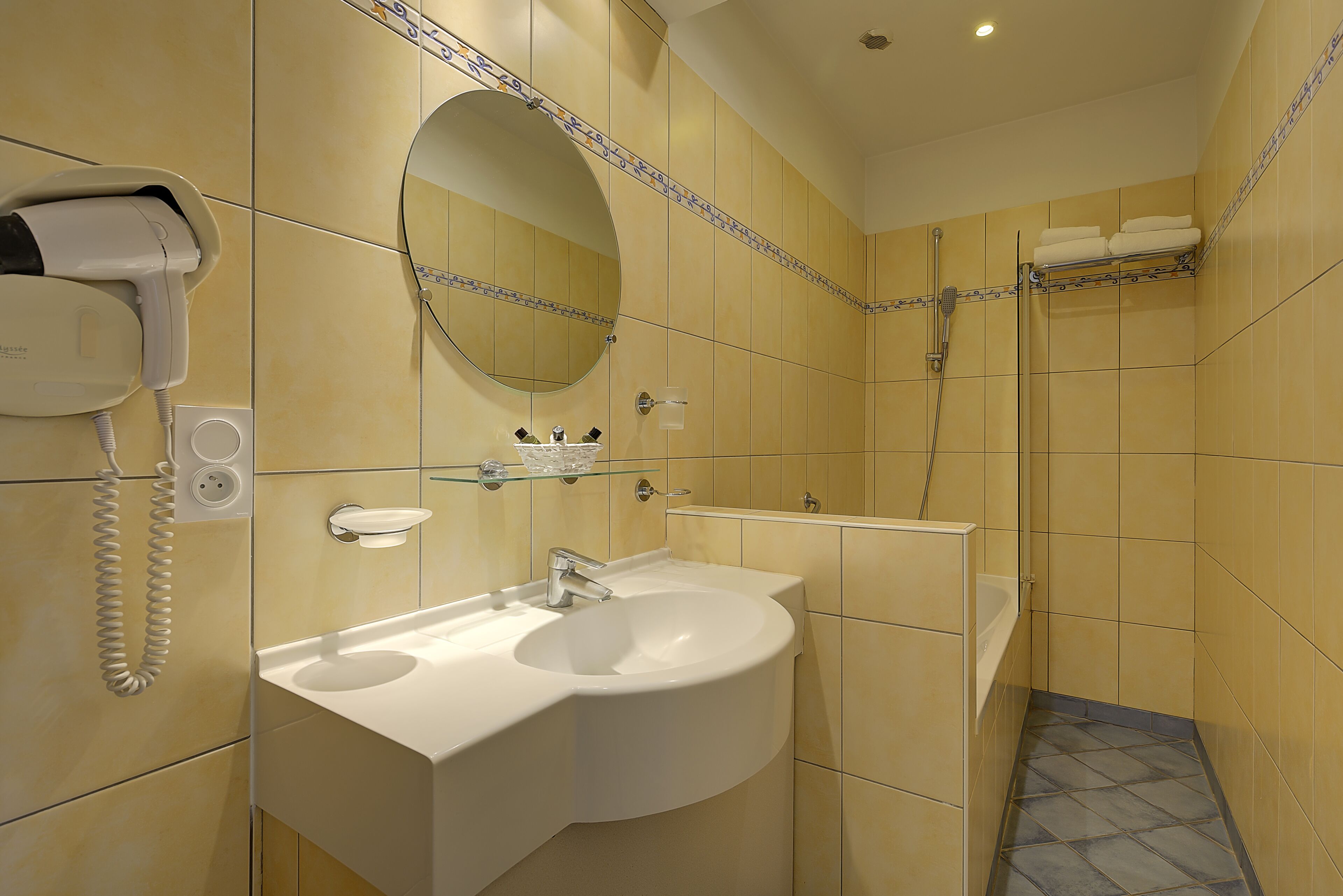 A bathroom with a sink, mirror, and shower.