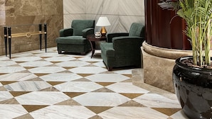 A lobby with a checkered floor, green armchairs, a glass table, and framed portraits on the wall. - City Seasons Suites (Dubai)