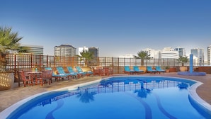 A rooftop pool with lounge chairs and a city skyline in the background. - City Seasons Suites (Dubai)