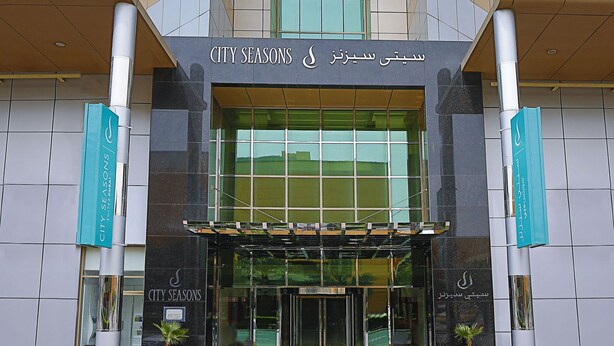 A modern hotel with a prominent entrance, glass facade, and a sign indicating it is a hotel. - City Seasons Suites (Dubai)