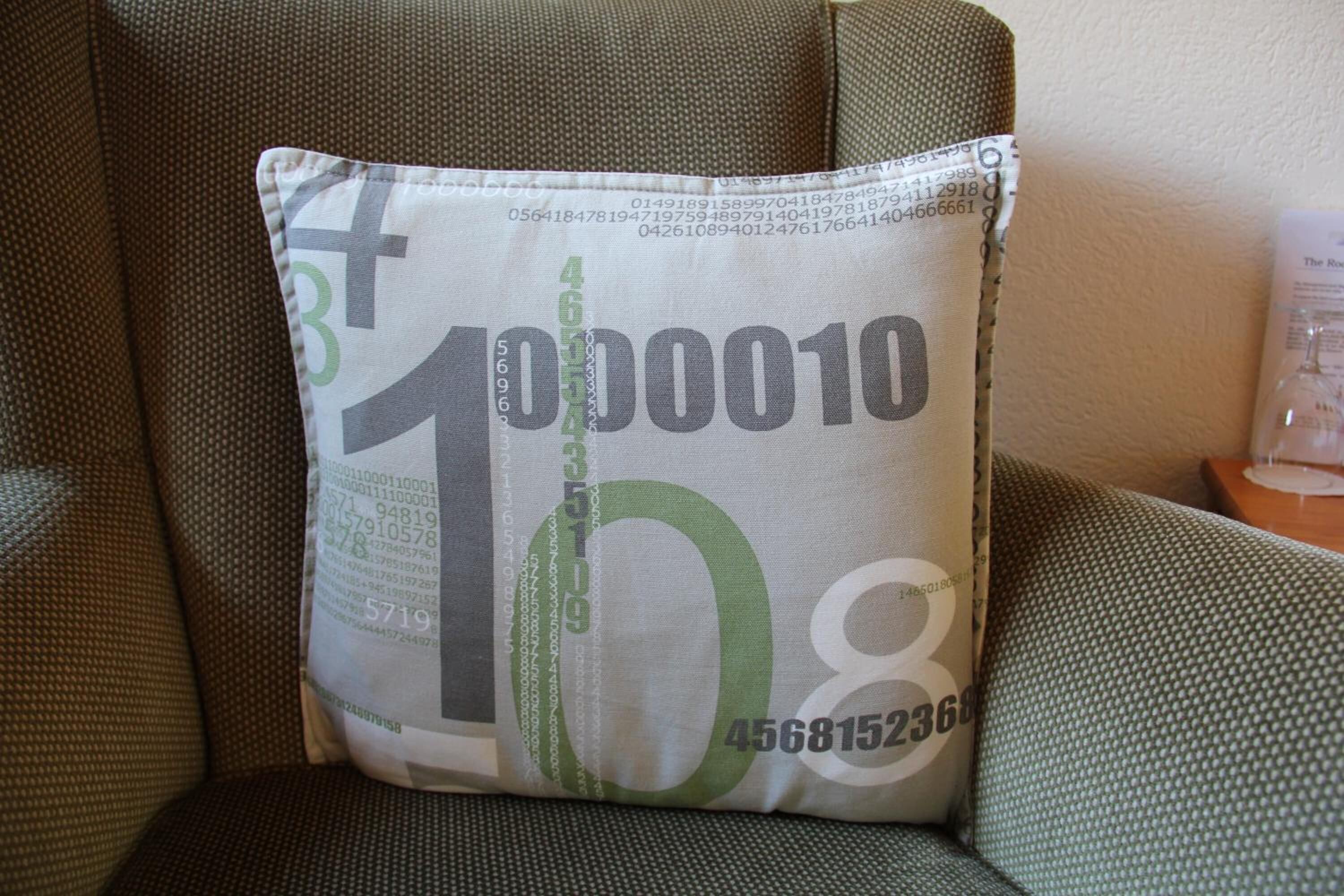 Un coussin orné d’un motif en code binaire et de chiffres, sur un tissu texturé.