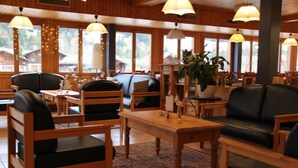 Un restaurante acogedor con mobiliario de madera, ventanas amplias y lámparas colgantes.