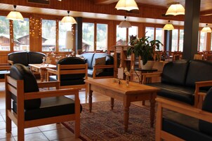 Um restaurante acolhedor com mobiliário de madeira, janelas amplas e luminárias pendentes.