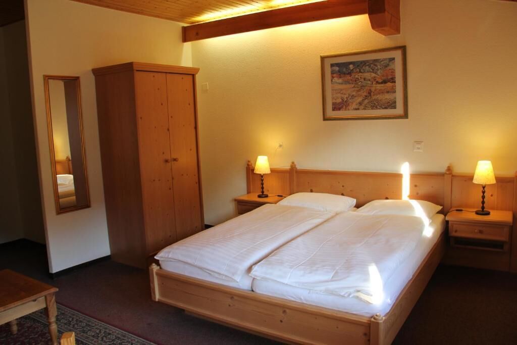 Une chambre à coucher avec un lit en bois, deux tables de chevet avec des lampes, une armoire et un tableau encadré au mur.