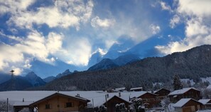 Un pueblo de montaña con casas de madera, un telesilla y árboles cubiertos de nieve.