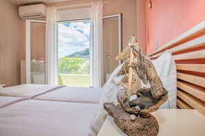 Une chambre d’hôtel avec deux lits, une tête de lit en bois, une sculpture décorative et une vue sur la verdure par la fenêtre.
