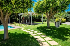 Un jardin bien entretenu, agrémenté d’une pergola, d’une piscine et d’un chemin en pierre.