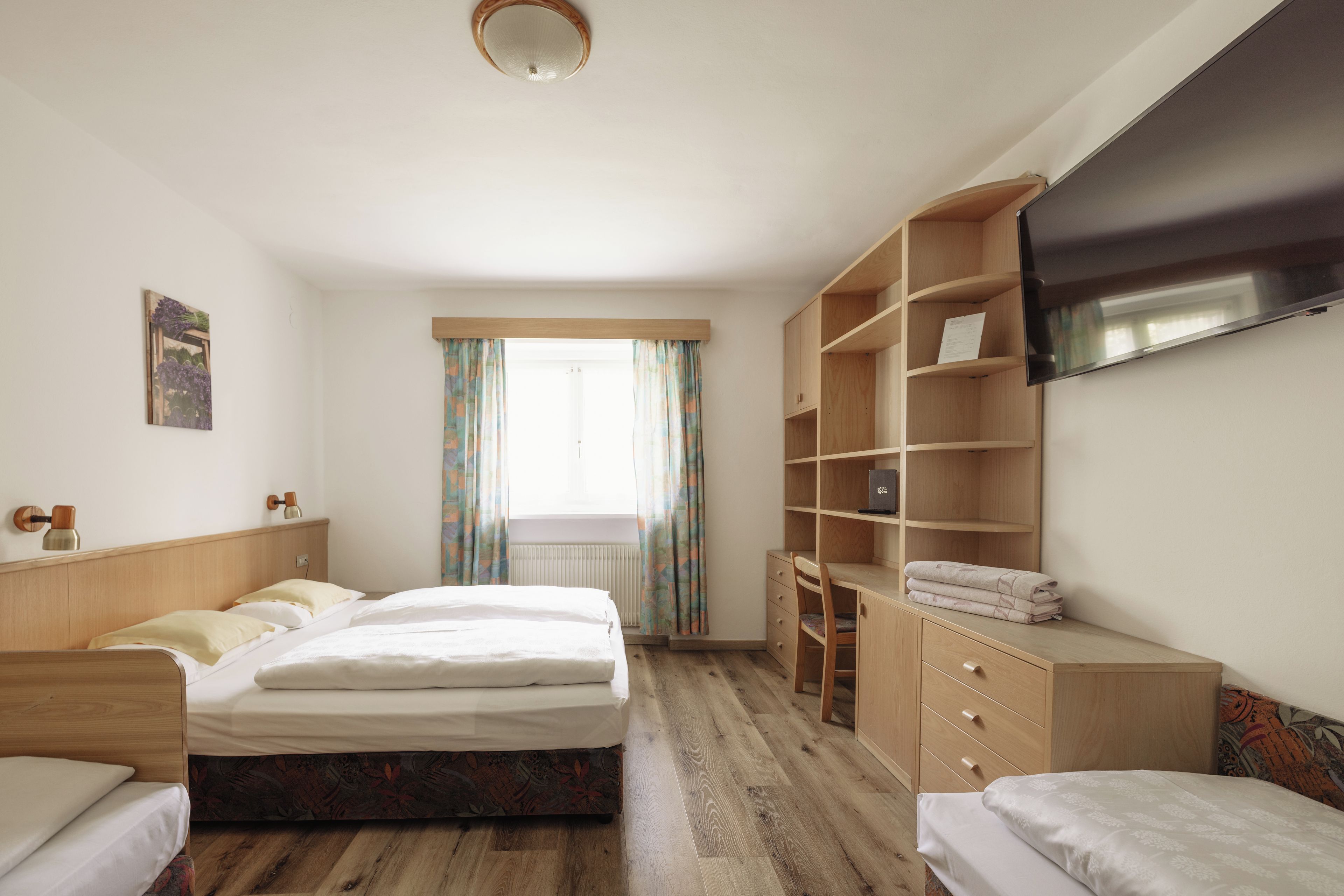 Una habitación de hotel con cama, escritorio, silla, televisión y armario.