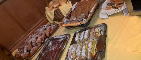 A buffet table with various baked goods including bread, pastries, and desserts.